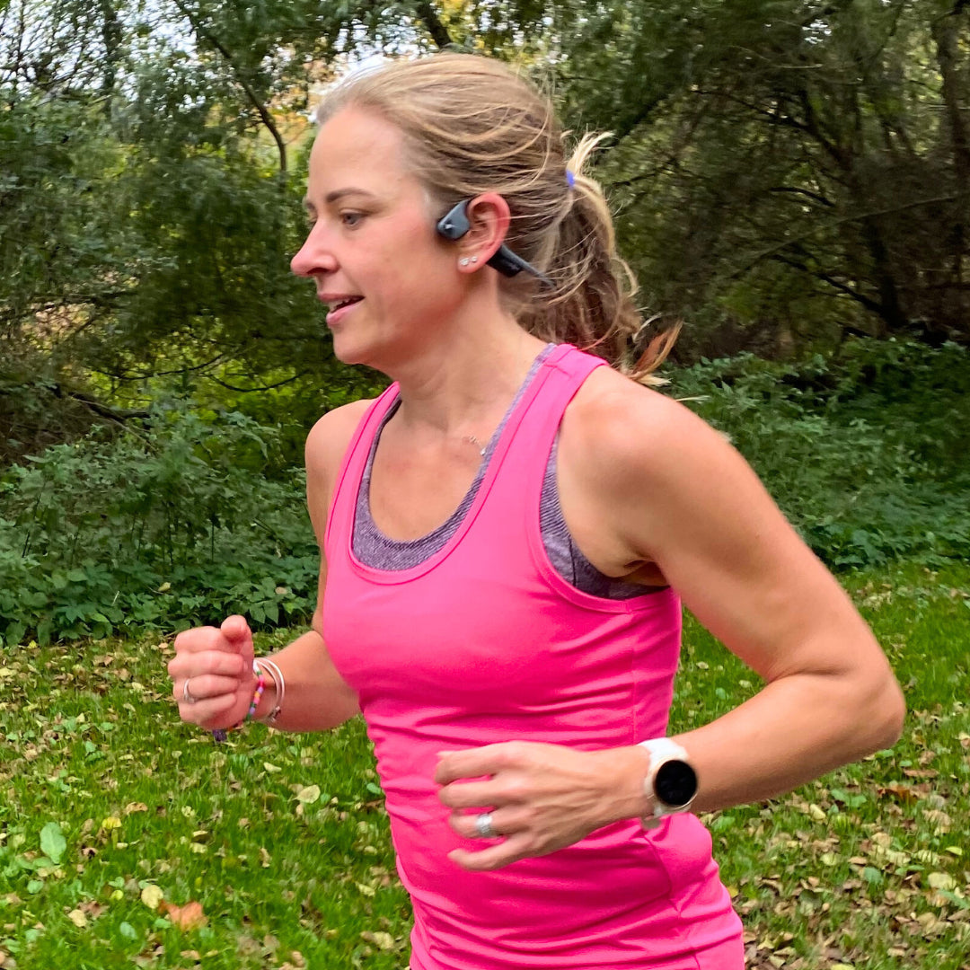 Kvinna som springer i skogen under ett pass i Bodily LÖPNING.