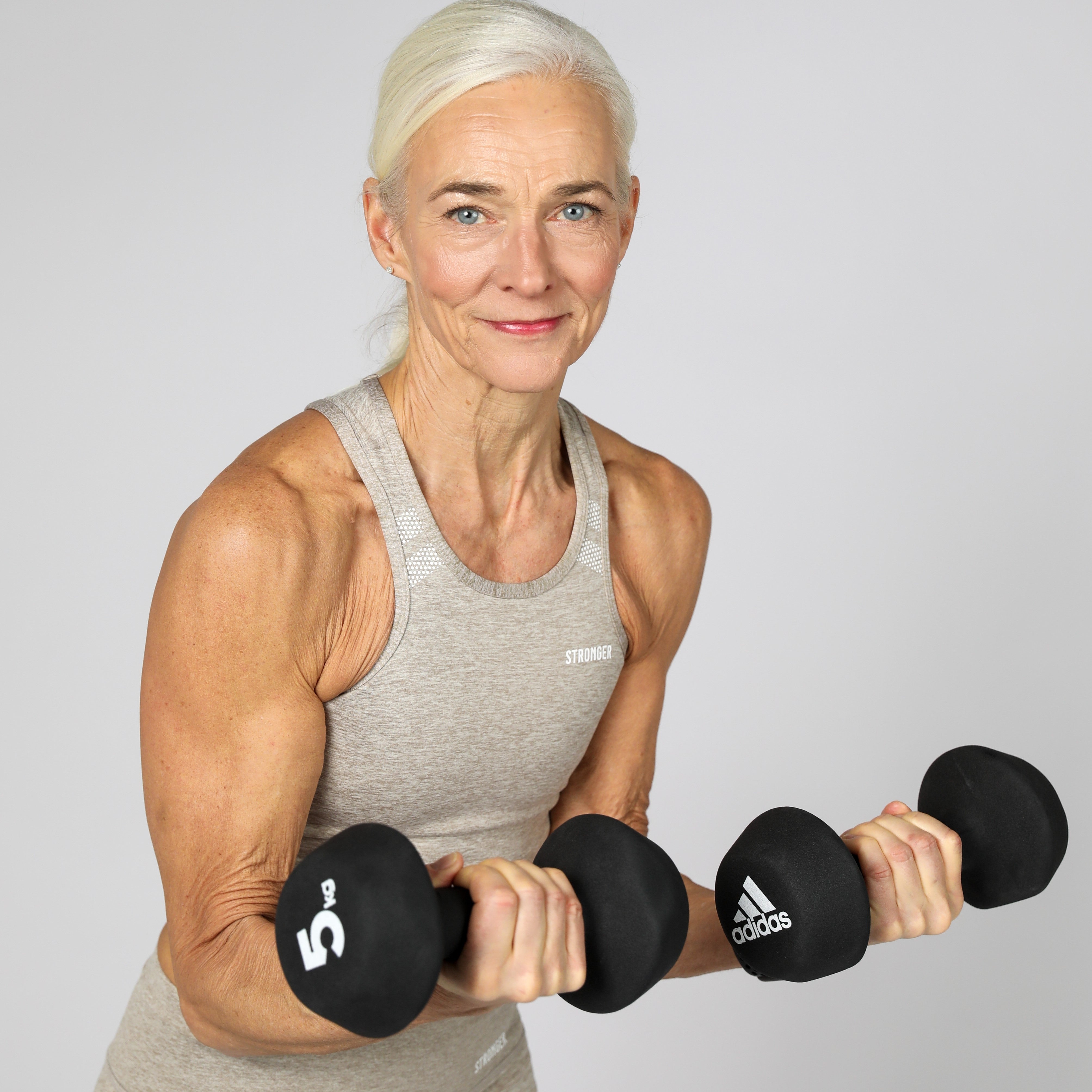 Person i träningskläder som tränar styrka med två hantlar.