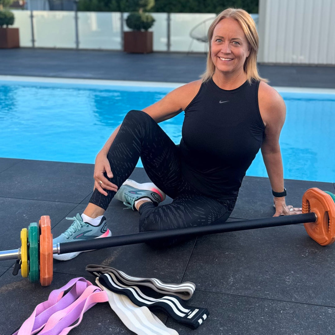 Kvinna tränar styrka med skivstång och gummiband i Bodily VIKTER-programmet.